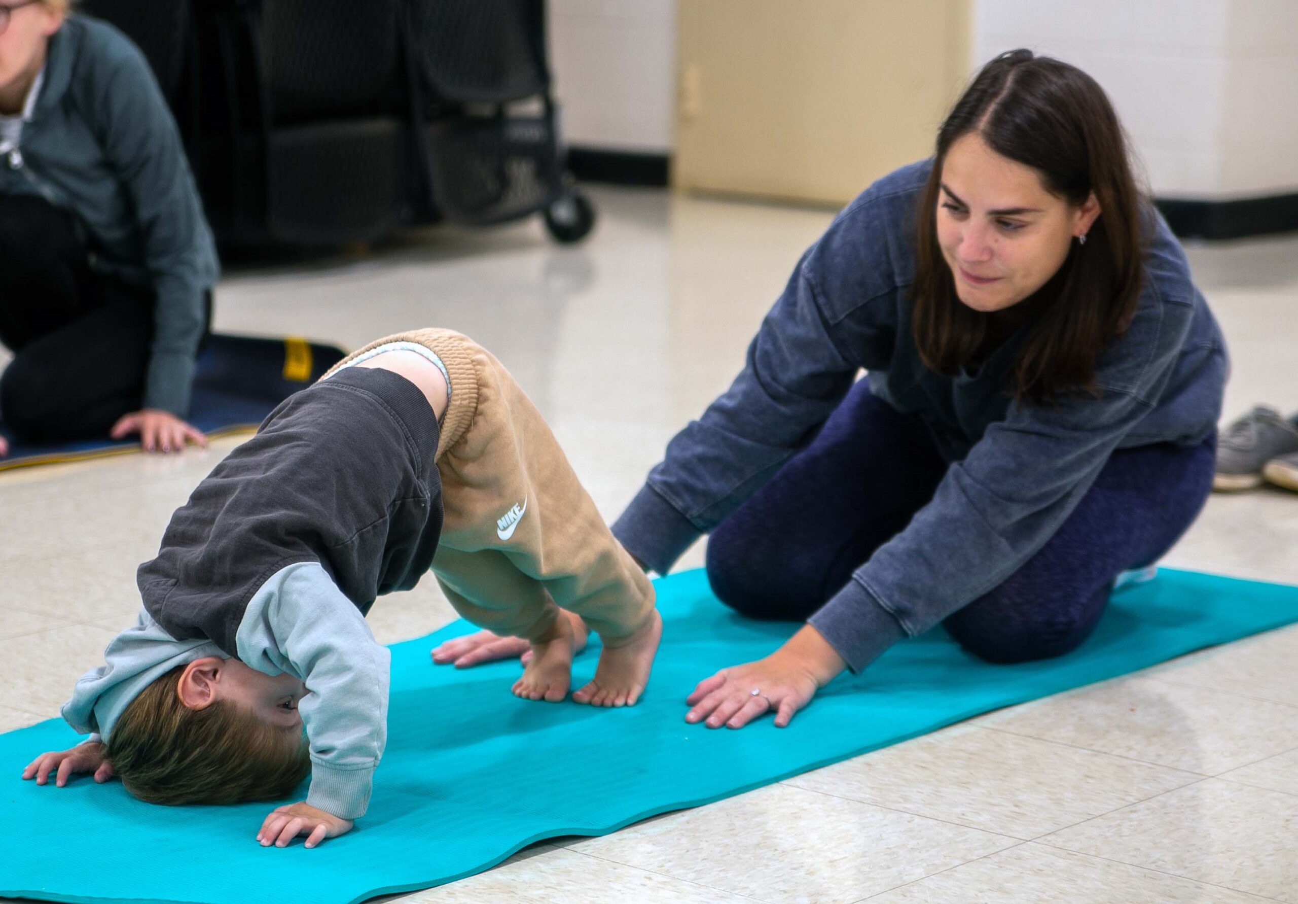 Mom helps toddler do yoga